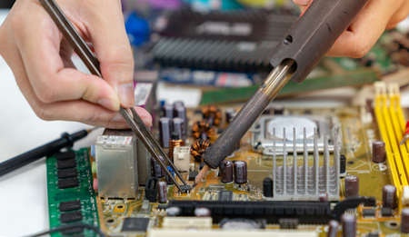 Technician repairing inside of mother board by soldering iron. the concept of data, hardware, technology.の写真素材