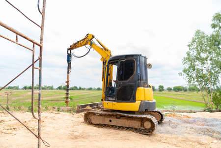 Drill excavator prepare digging fence posts around the factory.