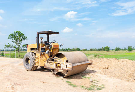 Road roller at construction site with cloudy blue sky during sunset.の写真素材