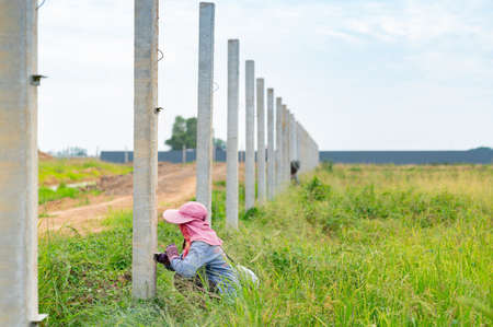 Workers measure the pole level to install metal sheet fences around factory..の写真素材