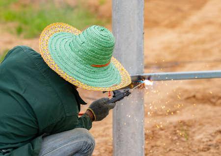 Workers weld metal support, install support metal sheet, make fences around the factory.の写真素材