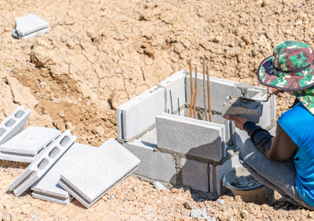 Construction workers apply mortar to the bricks to build the walls around the piles.の写真素材