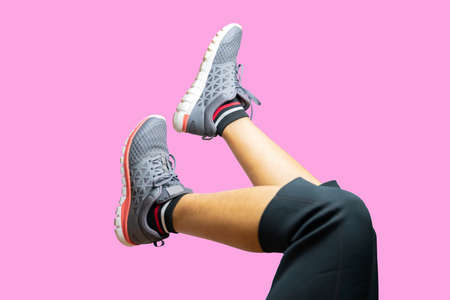 A woman doing cardio exercises in the gym on isolate pink background.