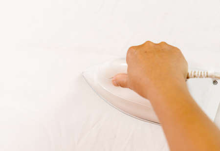 Women ironing clothes on ironing board in laundry room at homeの写真素材