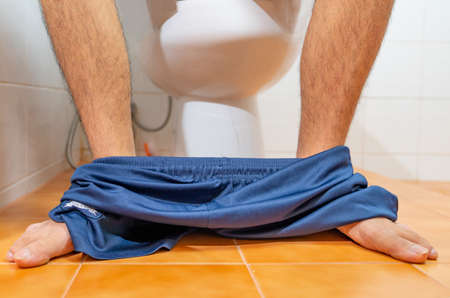 The leg of young man sitting on toilet bowl at home.の写真素材