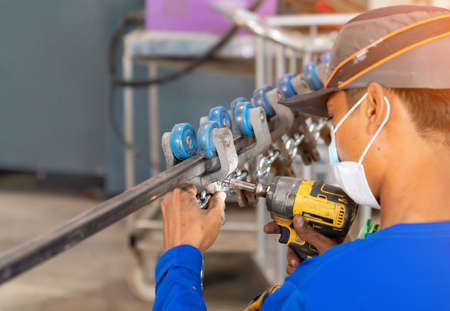 The technician use electric screw driver for tighten roller rail in factory.