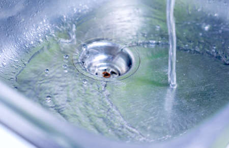Close up a clean water flows into the stainless steel sink.の写真素材