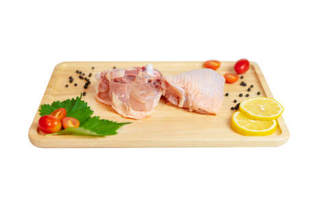 Raw chicken thigh with lamon and spices on wooden cutting board isolate white background.の写真素材