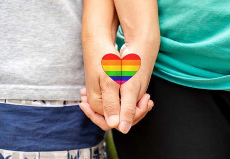 LGBTQ love symbol,Rainbow heart drawing on gay couple hand in hand.の写真素材