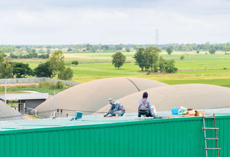 Workers Mounting leg support solar panel on roof in factory. on green tree background.の写真素材
