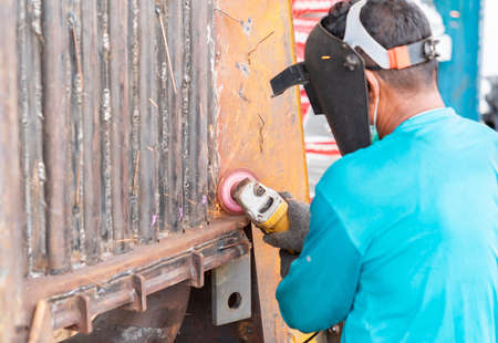 Worker cutting, grinding and polishing boiler machine with sparks outdoor workshop, close-up.の写真素材