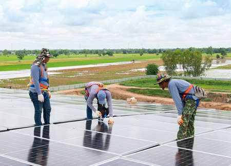 Technicians fitting solar panel on roof in factory under blue sky.の写真素材