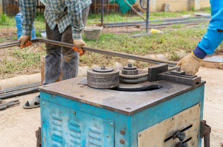 Worker using steel bending machine bender rebar for building structure pole.の写真素材