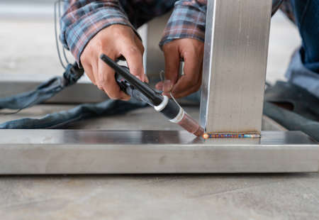Worker welding of table leg stainless steel with argon. Argon arc welding