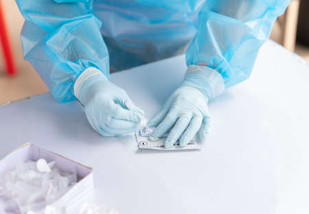 Sample tube and drops in the test device of covid 19 antigen self-test in holding hand.の写真素材