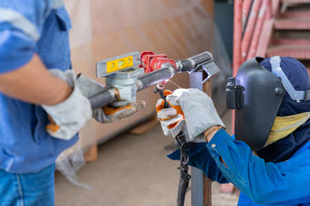 Industrial worker ware mask and gloves welding steel pipes with argon, welding mask close-up