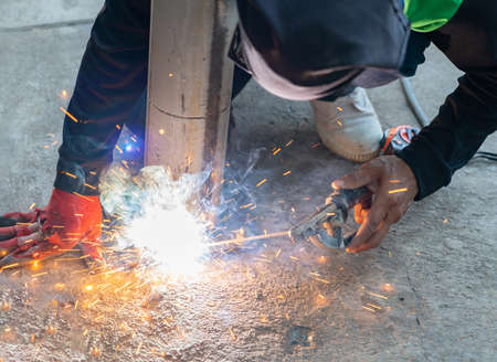 The Mechanic Is welding steel pole To Build A fence around machine In An Industry.