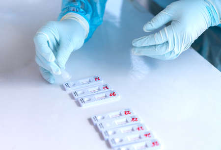 Medical personnel drop swab sample on ATK for find Corona virus 2019 on white desk.の写真素材