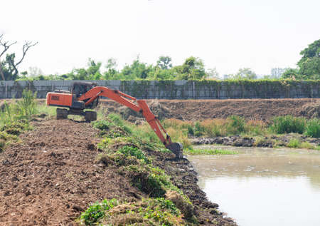 A backhoe excavator adjusts the edge of the pool to accommodate the treated water.の写真素材