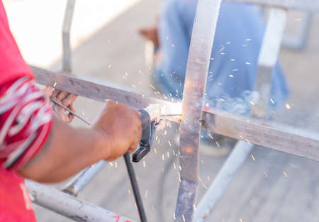 Workerwelding metal in workshop with sparks in factory.