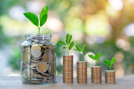 Money coin stack and in glass bottles with plants glowing.Saving money and investment concepts.の写真素材