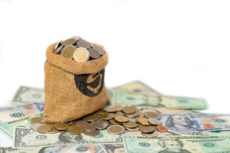 Coins in hemp sacks resting on piles of coins and dollar bills isolate white background. Saving Concept.の写真素材