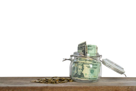 Saving jar with dollar billf saving and financial concept on wooden desk isolate white background and free space for your text.の写真素材