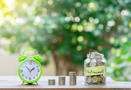Concept saving for retirement.Coins stack and alarm clock on out of focus background.の写真素材