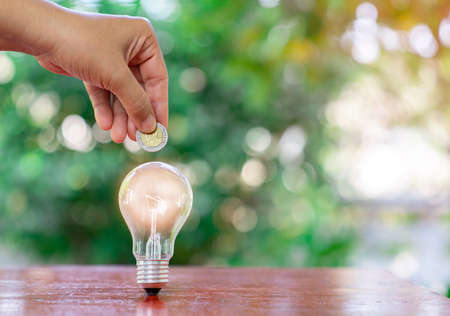 Inspiration saving money with light Bulb on out of focus background. Idea saving money and energy concept.の写真素材