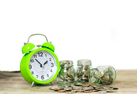 Alarm clock and coin in glass jar concept of money saving, invesment and retirement conceptの写真素材