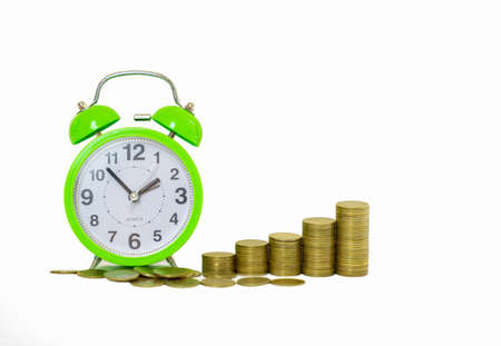 Stack of increasing coins with green alarm clock on isolate white background.の写真素材
