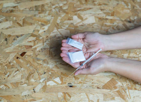 Drug and syringe in hold hand on wooden table. Drug conceptの写真素材