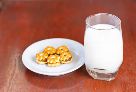 Plate with pine apple yam cookies and glass of milk on wooden backgroundの写真素材