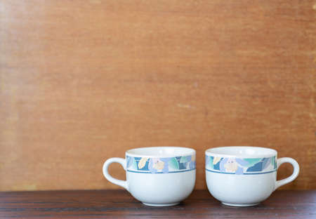 Two white cups on wood table with wood background. Concept about friendship, love and relationshipの写真素材