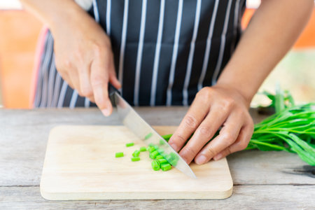 Woman cutting water spinach on wooden cutting board. Cooking at home.の写真素材