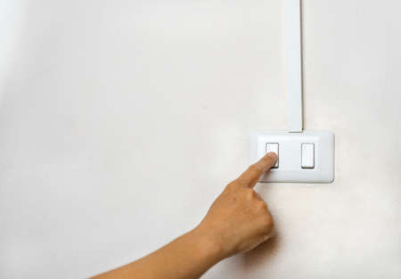 Close up of Female finger is turn off on lighting switch at home. Energy saving concept and Copy...