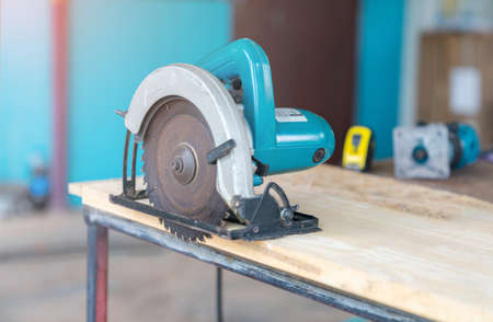 A circular saw lies on a wooden table in the workshop. A close-up of a circular sawの写真素材