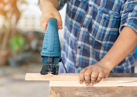 The carpenter working with a jigsaw on wood in the workshop.の写真素材
