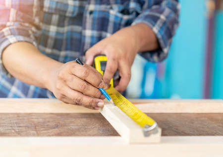 The man measuring tape on wooden frame on wooden table.の写真素材