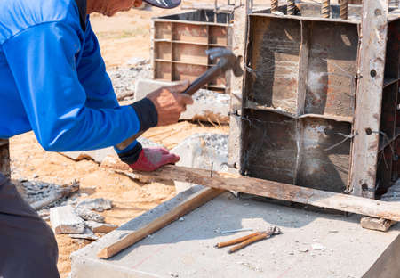 Worker hitting a nail wood support fram of pole in construction site.の写真素材