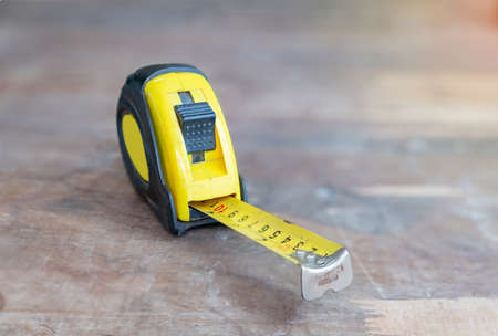 The yellow tape measure paste on wood table, out of focus background.の写真素材
