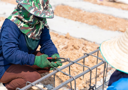 Worker wiring rebar steel rods for pour cement at the Building Site.の写真素材