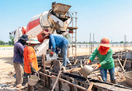 In construction site workers pour cement on beam frame work for building.の写真素材