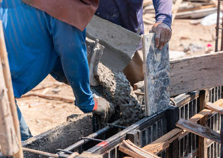 Workers pour mortar from the rails of cement trucks into beams framework in construction site.の写真素材