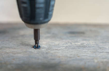 Closeup of screw being screwed into a wooden plank in workshopの写真素材