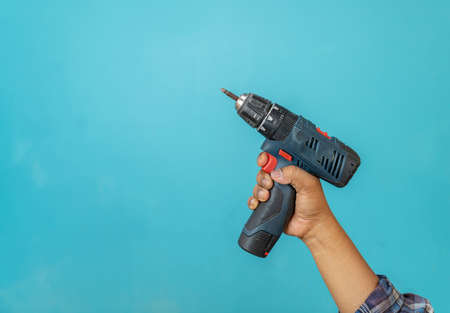 The carpenter holding a electric screwdriver on aqua blue background.の写真素材