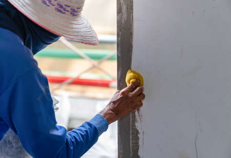Workers use a sponge to wipe the plaster on the windowsill of the room in factory.の写真素材