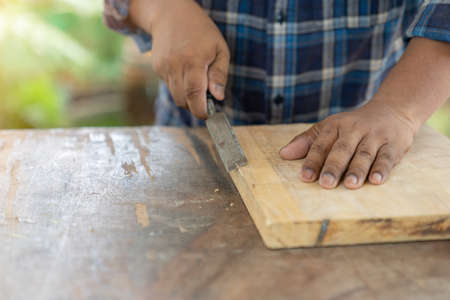 Cropped view of woodworker holding chisel wood in workshopの写真素材