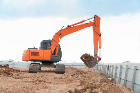 A Excuvator digging a trench for an underground fence pillar for set perpendicular.の写真素材