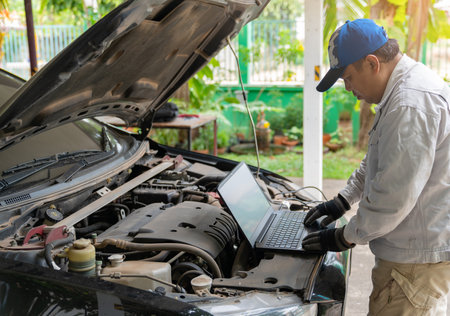 Mechanic Using Laptop While Examining Car Engine to adjust turbo.の写真素材